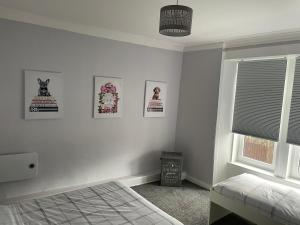 a bedroom with a bed and pictures on the wall at Bellshill , Belvidere central upper apartment in Bellshill
