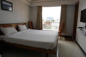 a bedroom with a bed and a large window at Kingscross Residency in Chennai