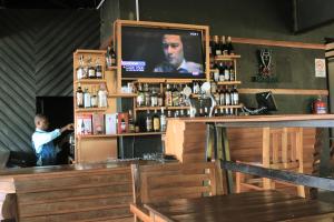 a man standing behind a bar with a television at REBERO RESORT Ltd in Kigali