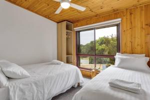 two beds in a room with a window at Doesntmatta - Beachside Breeze at St Andrews Beach in Saint Andrews Beach