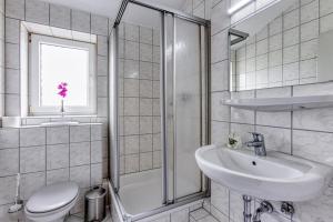 La salle de bains est pourvue d'un lavabo, de toilettes et d'une douche. dans l'établissement TOUCH DOWN Motel, à Lohmar