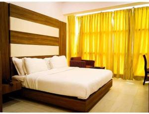 a bedroom with a large bed and a yellow window at Hotel Sobti Plaza, Ambala, Haryana in Ambāla