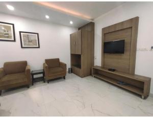 a living room with two chairs and a flat screen tv at Hotel Sobti Plaza, Ambala, Haryana in Ambāla