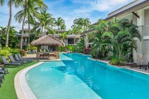 een zwembad voor een huis met palmbomen bij Lagoon Breeze Swim-out Temple Resort Stay in Port Douglas