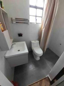 La salle de bains est pourvue de toilettes, d'un lavabo et d'une fenêtre. dans l'établissement Zen House, à Kakamega