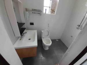 a white bathroom with a toilet and a sink at Zen House in Kakamega