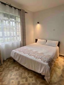 - une chambre avec un grand lit blanc et une fenêtre dans l'établissement Zen House, à Kakamega