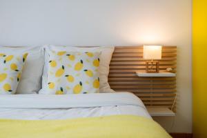 Una cama con almohadas amarillas y blancas y una lámpara. en Lille gares studio avec parking sécurisé en Lille
