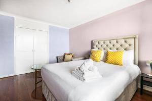 a bedroom with a large white bed with yellow pillows at Two Stunning Bedrooms & Private Balcony & River View in London