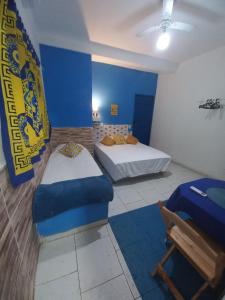 Habitación con 2 camas y pared azul en OLHO GREGO Hospedagem em ARRAIAL d'AJUDA, en Arraial d'Ajuda