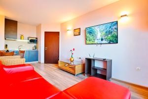 ゴールデン・サンズにあるLuxury Apartment Zlatna Kotvaのリビングルーム(赤いソファ、テレビ付)