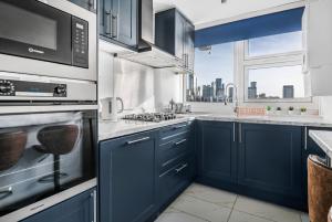 a kitchen with blue cabinets and a large window at Two Stunning Bedrooms & Private Balcony & River View in London