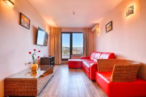 Una sala de estar con un sofá rojo y una mesa. en Luxury Apartment Zlatna Kotva, en Golden Sands