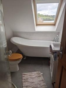 bagno con vasca, servizi igienici e finestra di Top Floor Flat Ceol Na Mara (Music of the Sea) a Rosemarkie