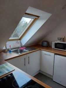an attic kitchen with a sink and a window at Top Floor Flat Ceol Na Mara (Music of the Sea) in Rosemarkie
