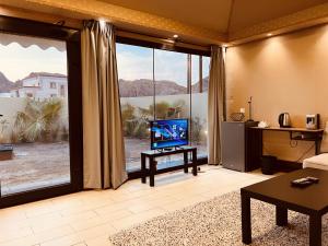 - un salon avec une télévision et une grande fenêtre dans l'établissement ONE Elegant Cottage near the Beach, à Mascate