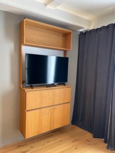 TV de pantalla plana en la parte superior de un centro de entretenimiento de madera en UPTOWN Hotel Apartments, en Estocolmo