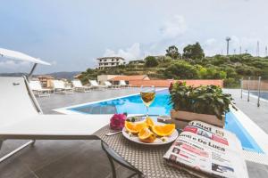 una mesa con una copa de vino y naranjas junto a una piscina en "Il Segreto" Vista Panoramica sulle Isole Eolie con Piscina, palestra e WiFi, en Patti