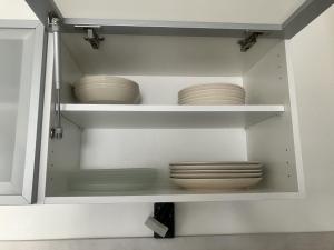 a cabinet filled with plates and bowls on shelves at maison entre plage marais et forêt in Olonne-sur-Mer +10 photos