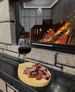 a glass of wine and a plate of meat and bacon at Hotel SH & SH in Pukë