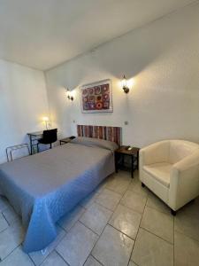 sypialnia z łóżkiem, kanapą i krzesłem w obiekcie Hotel Alexander w Perpignanie