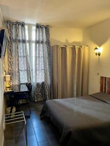 a bedroom with a bed and a desk and a window at Hotel Alexander in Perpignan