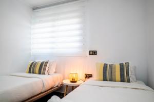 1 dormitorio con 2 camas y ventana con lámpara en Tranquilidad a la orilla del mar, en Villajoyosa