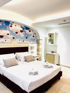 - une chambre avec un grand lit orné d'une fresque murale représentant les nuages dans l'établissement Relais Porta del Sud, à Ostuni