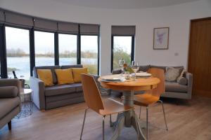 a living room with a table and chairs and a couch at The Angel - Luxury Lakeside Lodge in Cotham