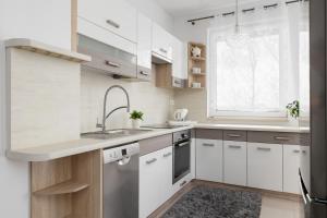 a kitchen with white cabinets and a sink and a window at Modern Apartment with Parking in Cracow by Rent like home in Kraków
