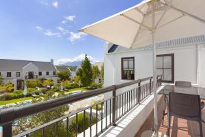 a balcony with a table and an umbrella at Winelands Golf Lodges 21 in Stellenbosch