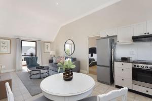 cocina y sala de estar con mesa, cocina y sofá en Winelands Golf Lodges 21, en Stellenbosch