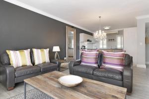 Sala de estar con 2 sofás de cuero y mesa de centro en Winelands Golf Lodges 24, en Stellenbosch