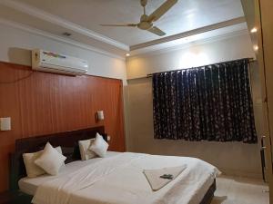 een slaapkamer met een bed, een plafondventilator en een raam bij gargi vill guest house in Pune