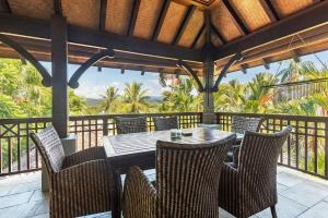 una mesa de madera y sillas en un balcón con vistas en Coco Villa - Central Mediterranean-style Pool Oasis, en Port Douglas