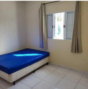 a small bedroom with a blue bed and a window at Casa De Hóspede in Itu