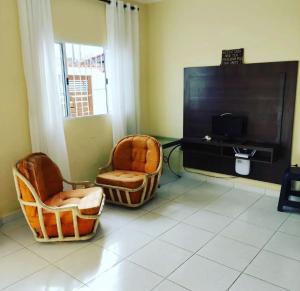 a living room with two chairs and a flat screen tv at Casa De Hóspede in Itu