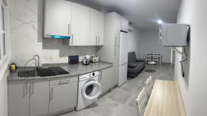 uma cozinha com armários brancos e uma máquina de lavar e secar roupa em Apartamento Tejares 2B em Málaga