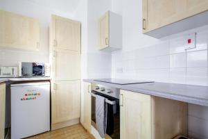 cocina con armarios blancos y nevera blanca en Chester Stays - Best Value Apartment with Free Parking in the heart of Chester, en Chester