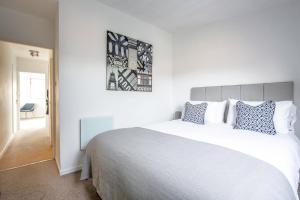 een slaapkamer met een groot wit bed met blauwe kussens bij Chester Stays - Best Value Apartment with Free Parking in the heart of Chester in Chester
