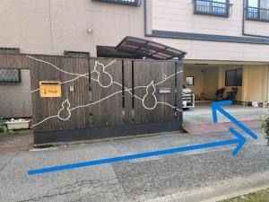a gate with blue arrows and a gate with a fence with a house at Show和の宿つちや～豊臣の隠れ茶の間～ in Nagoya