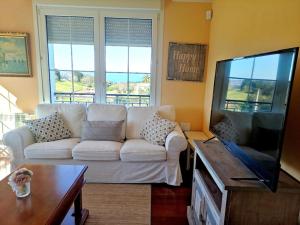 uma sala de estar com um sofá branco e uma televisão de ecrã plano em Chalet con magníficas vistas al mar em Perlora