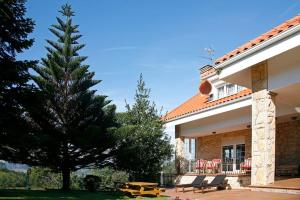 a house with a pine tree in the yard at Chalet con magníficas vistas al mar in Perlora