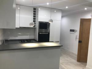 a kitchen with white cabinets and a black refrigerator at PrG Apartments in Praia