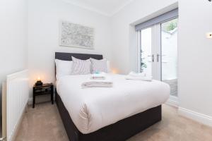 a bedroom with a large white bed and a window at Vibrant 1BR Apt wPrivate Decked Garden, Fast WIFI in London
