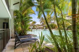 une terrasse avec une chaise, des palmiers et une piscine dans l'établissement Sunny Swim-out Serenity with Direct Beach Access, à Port Douglas