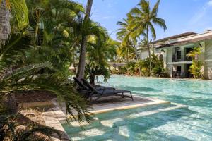 - une piscine avec un banc et des palmiers dans l'établissement Sunny Swim-out Serenity with Direct Beach Access, à Port Douglas