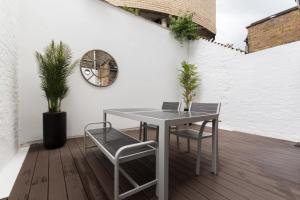 a table and chairs on a patio with a clock at Vibrant 1BR Apt wPrivate Decked Garden, Fast WIFI in London