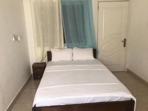 a bed with white sheets and pillows in a room at Violettes Villa in Accra