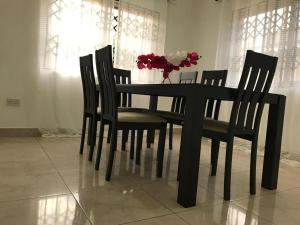 a black table with chairs and a vase of flowers at Violettes Villa in Accra